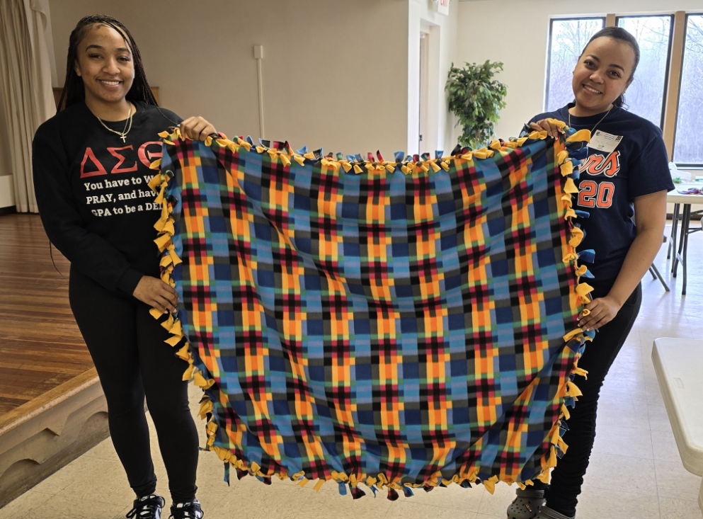 Volunteers holding up a no-sew fleece Comfort Blanket, made for a newly grieving donor family