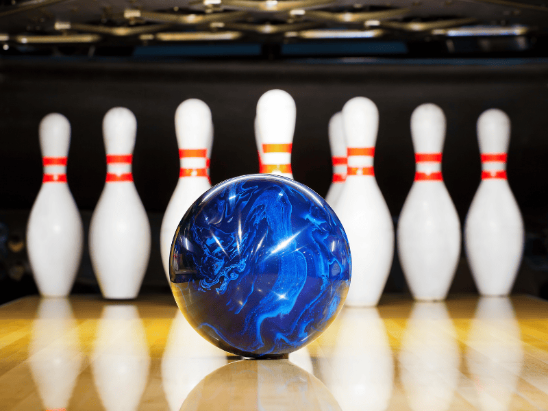 A blue bowling ball heads toward 10 pins