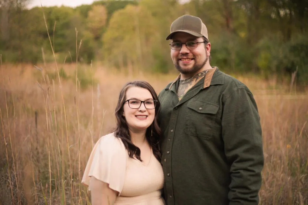 Madison Dargitz and her husband, Tyler, stand in a field of dry grasses.