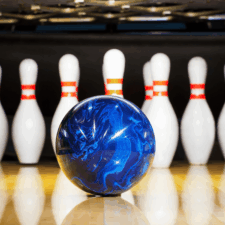 A blue bowling ball heads toward 10 pins